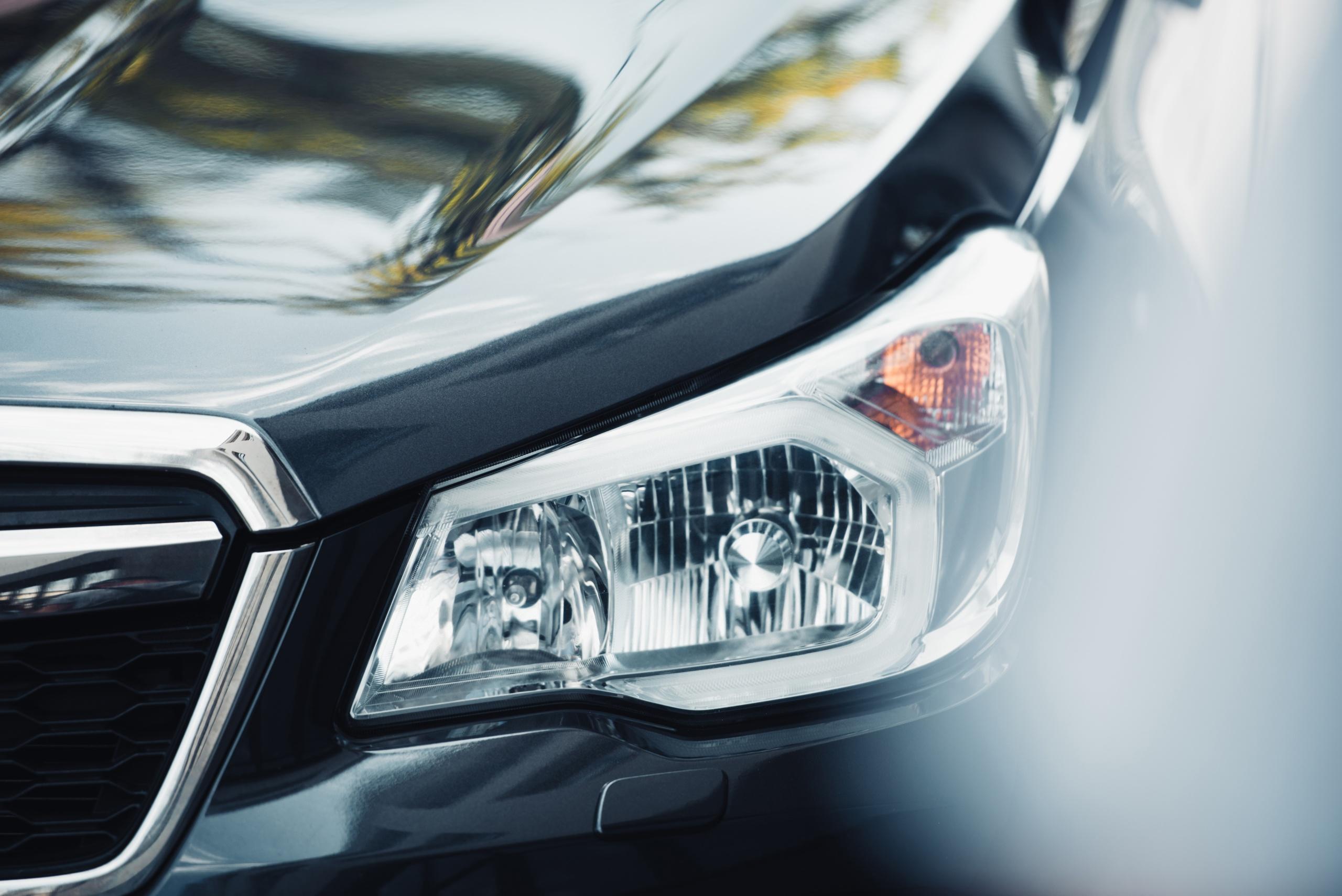 Selective focus of headlamp and capote of black modern car